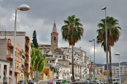 Blick auf Albaida mit weißen Häusern, Palmen und einem Turm auf dem Hügel.