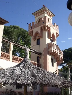 Tower with balconies and a roof in Benicasim, with a thatched roof in the foreground.