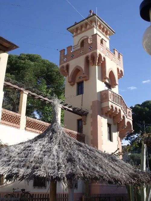 Tower with balconies and a roof in Benicasim, with a thatched roof in the foreground.