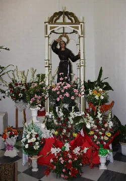 Estatua de la Santa de Alcolea con flores en un altar.