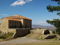 Heiligtum der Jungfrau vom Tremedal in Orihuela del Tremedal, mit Landschaft und blauem Himmel.