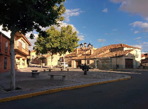 Square with benches, trees, and houses in Espirdo, Segovia.