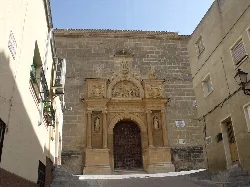 Fachada del convento con puerta de madera y detalles en piedra.
