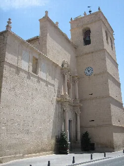 Fassade der Kirche mit Glockenturm und Uhr in Muchamiel.