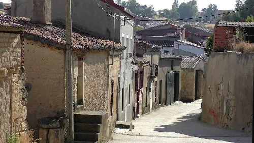 Blick auf eine enge Straße in Cuelgamures mit alten Häusern und Steinmauern.