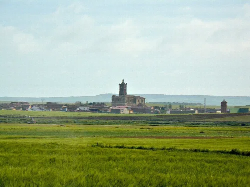 Landscape with green meadows and a church in the distance.