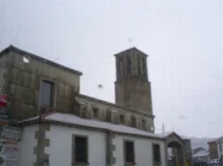 Church with stone bell tower and snowy roof in Vallejera de Riofrío.