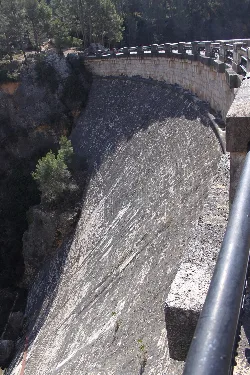 Vista de la presa del embalse de Buseo en Chera, con agua y vegetación alrededor.