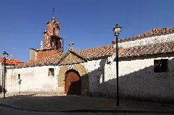 Iglesia blanca con puerta de arco y campanario de ladrillo en Mozárbez.