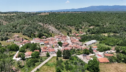 Aerial view of a village with houses and roads surrounded by nature.