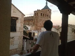 Junger Mann auf einem Balkon blickt auf die Kirche in Moral de Calatrava.