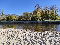 Sand beach with trees and river in the background.