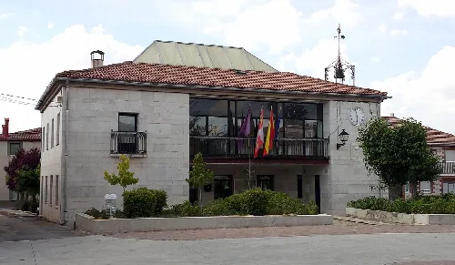 Town hall building with flags and gardens at the entrance.
