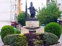Escultura de Sant Hipòlit en una plaza con arbustos verdes.