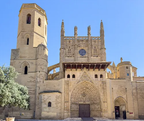 Außenfassade der Kathedrale von Huesca mit gotischer Tür und Türmen.
