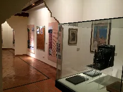 Sala del museo con cuadros y una cámara antigua en una vitrina.