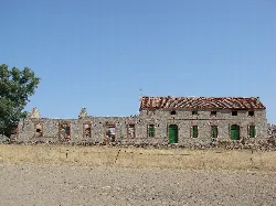 Steingebäude mit grünen Türen und Fenstern, Überreste einer alten Fabrik.
