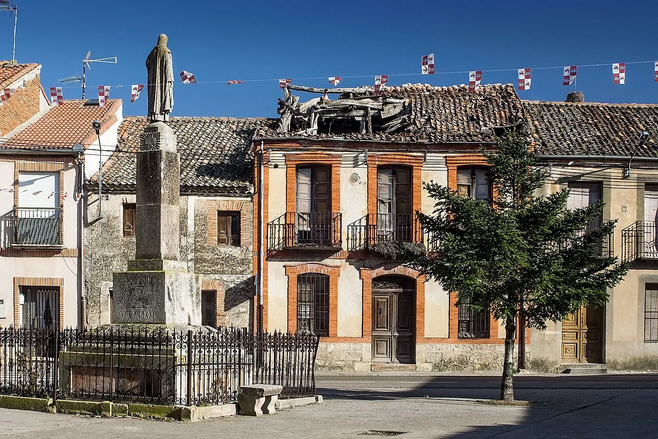 Square in Veganzones with statue, trees, and old buildings.
