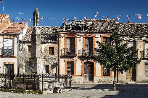 Square in Veganzones with statue, trees, and old buildings.