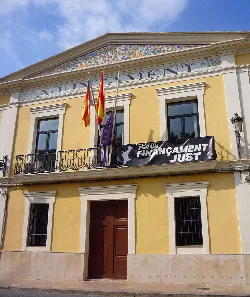 Edificio del ayuntamiento de Manises con banderas y pancarta en la fachada.