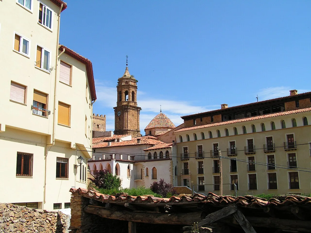 Calles y iglesia en La Iglesuela del Cid, Teruel, con edificios antiguos y torre de campanario.