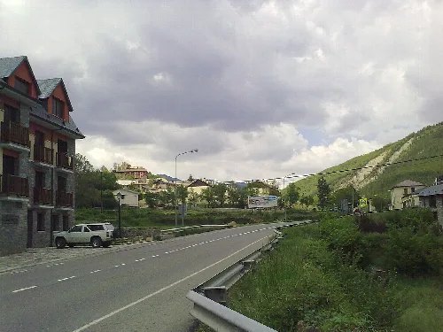 Blick auf die Hauptstraße in Castiello de Jaca mit Häusern und Bergen.