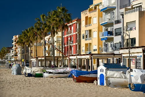 Barcos en la arena junto a edificios de colores en Torredembarra.