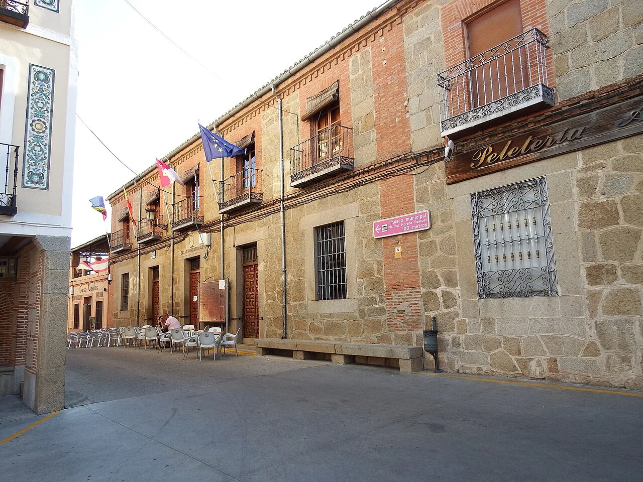 Straße mit Steingebäuden und Tischen auf dem Bürgersteig in Lagartera, Toledo.