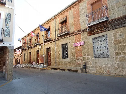 Street with stone buildings and tables on the sidewalk in Lagartera, Toledo.
