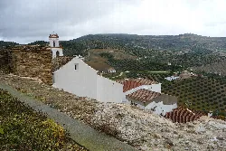 White church on a hill with rural landscape and hills in the background.