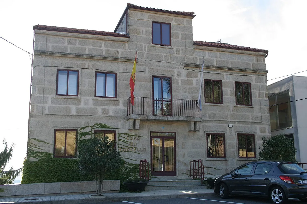 Steinernes Gebäude mit spanischer Flagge und Auto vor dem Gebäude.