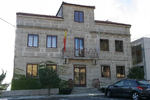 Steinernes Gebäude mit spanischer Flagge und Auto vor dem Gebäude.