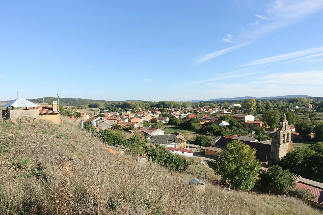 Vista panorámica de Castrocalbón con casas, iglesia y paisaje rural.