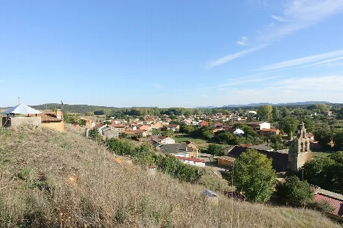 Panoramablick auf Castrocalbón mit Häusern, Kirche und ländlicher Landschaft.