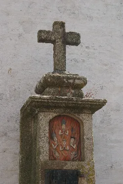 Steinernes Gehäuse mit Kreuz oben und religiöser Malerei auf der Vorderseite.