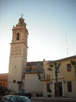 Iglesia y ayuntamiento de Museros con cielo despejado y palmeras.