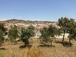 Blick auf Häuser und Bäume in Villar del Rey mit Hügeln im Hintergrund.