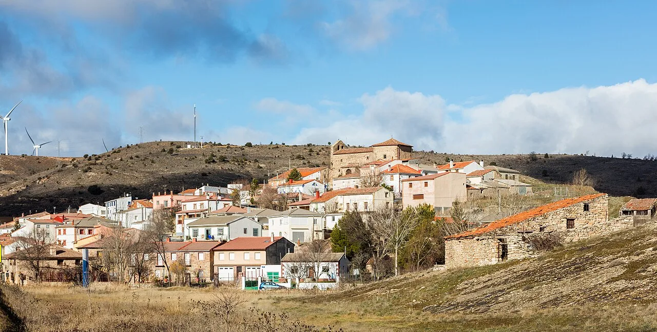 View of white houses in Anquela del Ducado with hills and blue sky.