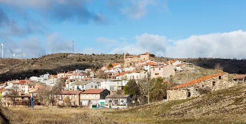 Vista de casas blancas en Anquela del Ducado con colinas y cielo azul.
