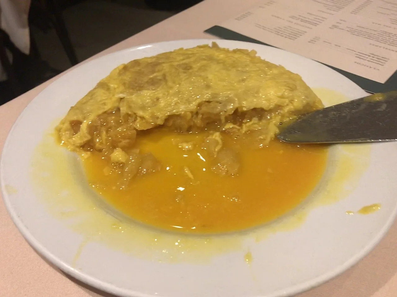 Kartoffelomelett mit flüssiger Textur auf einem weißen Teller.