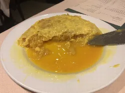 Kartoffelomelett mit flüssiger Textur auf einem weißen Teller.