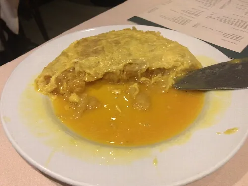Kartoffelomelett mit flüssiger Textur auf einem weißen Teller.