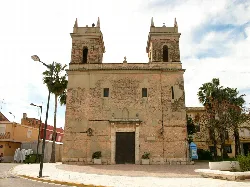 Facade of a church with two towers and aged walls in Sollana.