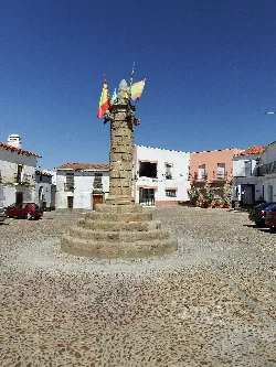 Monument in Garciaz square with white houses and cars.