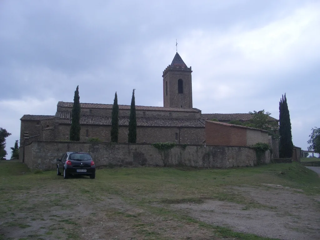 Iglesia románica con torre y árboles a su alrededor en Sagás.