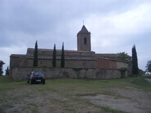 Romanische Kirche mit Turm und Bäumen drumherum in Sagás.