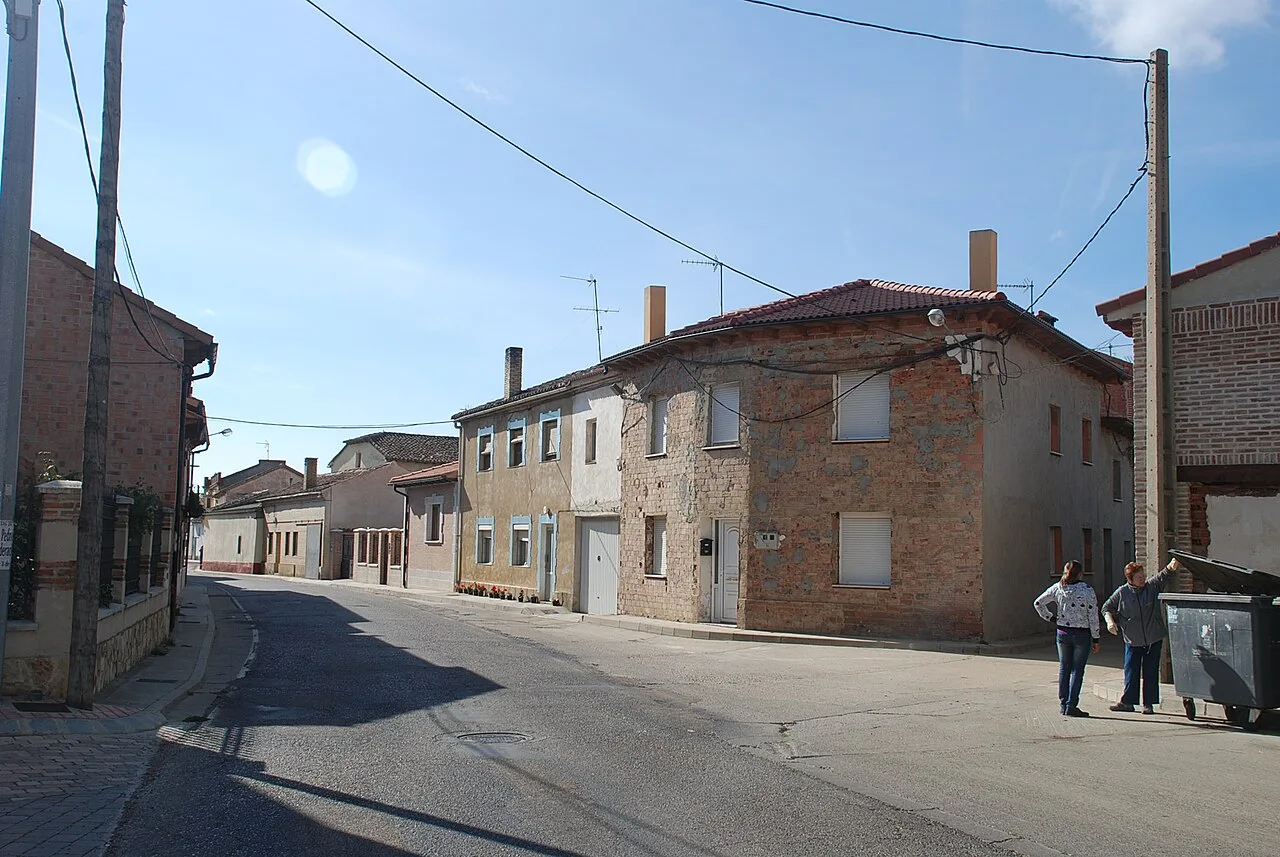 Street in Villaluenga de la Vega with stone houses and two people walking.