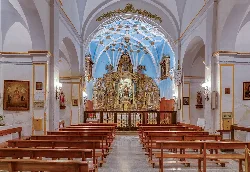 Innenraum einer Kirche mit goldenem Altar und Holzbänken.