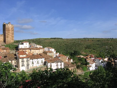 Weiße Häuser und ein Turm in Vozmediano, Soria, unter blauem Himmel.