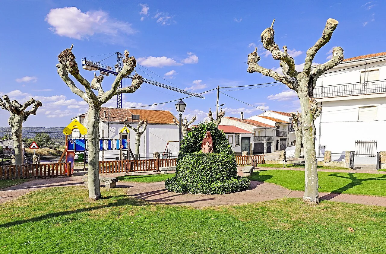 Park with pruned trees, sculpture, and children's play area in Ledrada.